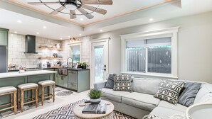 A modern kitchen with a central island, bar stools, and a dining area with a sofa and a coffee table. - Walk to Zilker Park, Barton Springs Pool! Cozy Gem (Austin)