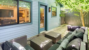 A covered patio area with outdoor seating, a door leading to an interior room, and a wooden fence. - Walk to Zilker Park, Barton Springs Pool! Cozy Gem (Austin)