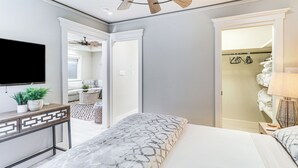 A bedroom with a bed, a TV, a ceiling fan, a bedside table with a lamp, and a closet with hanging clothes. - Walk to Zilker Park, Barton Springs Pool! Cozy Gem (Austin)