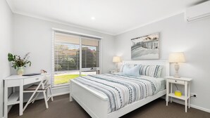 Een slaapkamer met een bed, twee nachtkastjes, een bureau en een stoel.