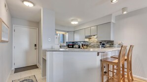 Uma cozinha moderna com ilha central, cadeiras de madeira e iluminação embutida.