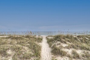 A sandy beach path leading to the ocean, surrounded by low dunes and sparse vegetation. - Sea 11 - Private Oceanview Deck & Community Pool (Carolina Beach)