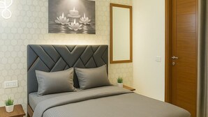 Quarto com cama, mesa de cabeceira, ar-condicionado fixado na parede, quadro emoldurado e porta de madeira.