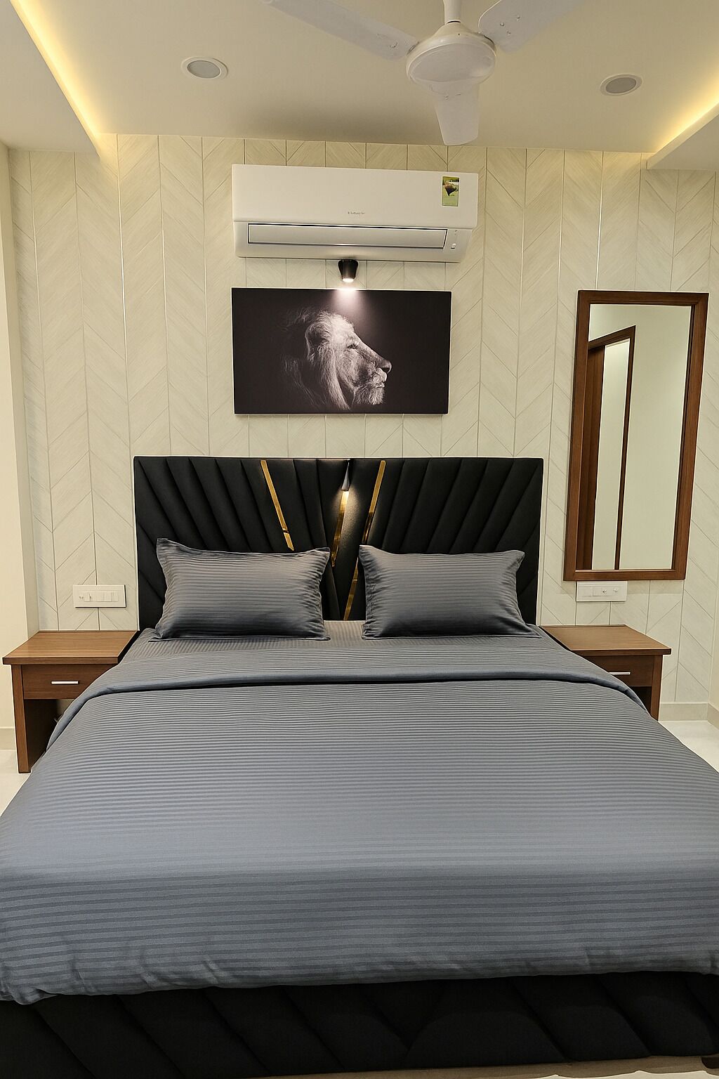Un dormitorio moderno con una cama grande, aire acondicionado instalado, televisor montado en la pared y ventilador de techo.