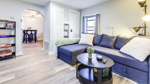 Een moderne woonkamer met een hoekbank, een ronde salontafel en een boekenkast.