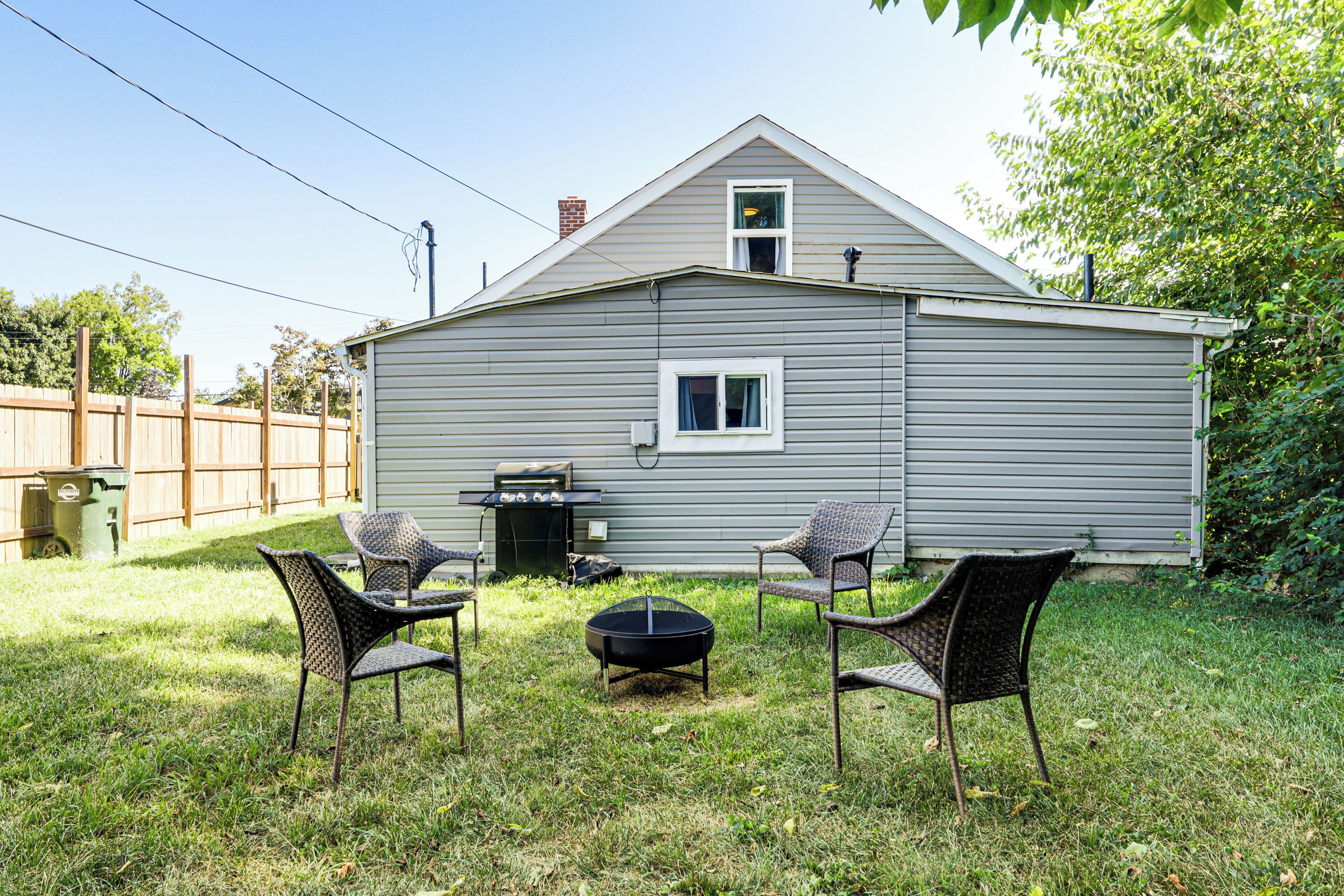 Ein Haus mit Garten, das einen Grill, zwei Stühle und eine Feuerstelle zeigt.