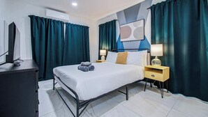 A modern hotel room with a bed, two bedside tables, a TV, and a large window with curtains.