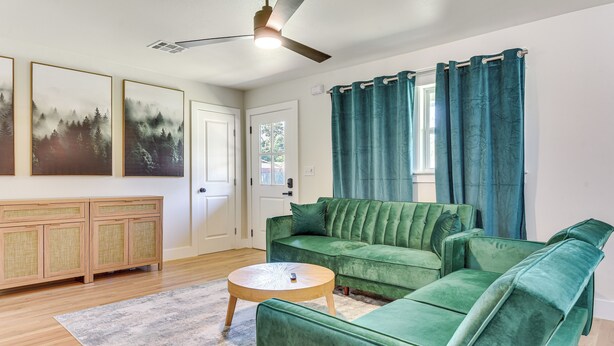 A living room with a green sofa, a wooden cabinet, and a ceiling fan. - 12 Mi to BOK Center: Pet-friendly Home w/ Yard! (Tulsa)