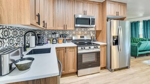 A modern kitchen with wooden cabinets, stainless steel appliances, and a patterned backsplash. - 12 Mi to BOK Center: Pet-friendly Home w/ Yard! (Tulsa)