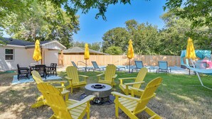 A backyard with a fire pit surrounded by yellow Adirondack chairs, a wooden fence, and a trampoline. - 12 Mi to BOK Center: Pet-friendly Home w/ Yard! (Tulsa)
