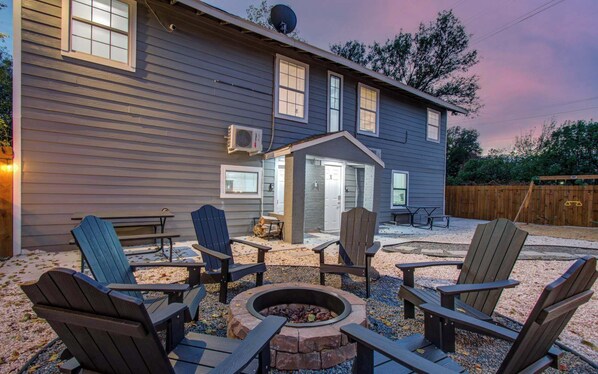 A house with a fire pit, outdoor seating, and a covered entryway.