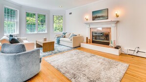 A spacious living room with a fireplace, large windows, and a cozy seating area.