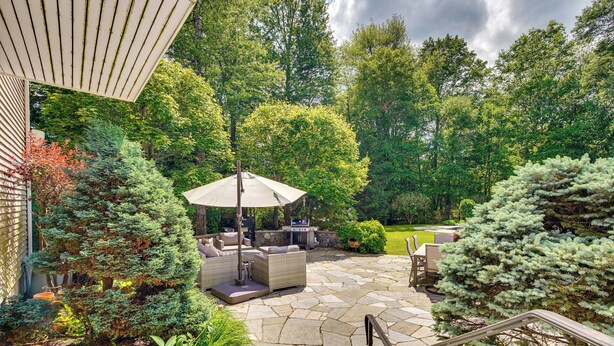 A patio with stone flooring, outdoor furniture, and a grill area.