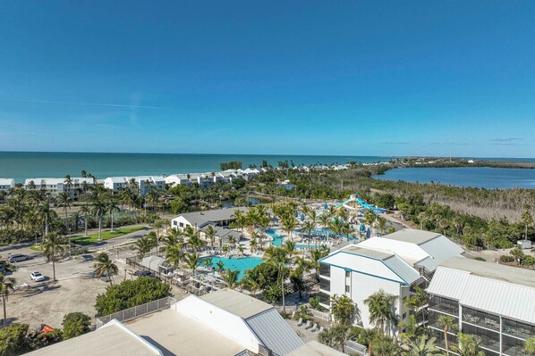 A resort with multiple buildings, a central pool area, and a view of the ocean.