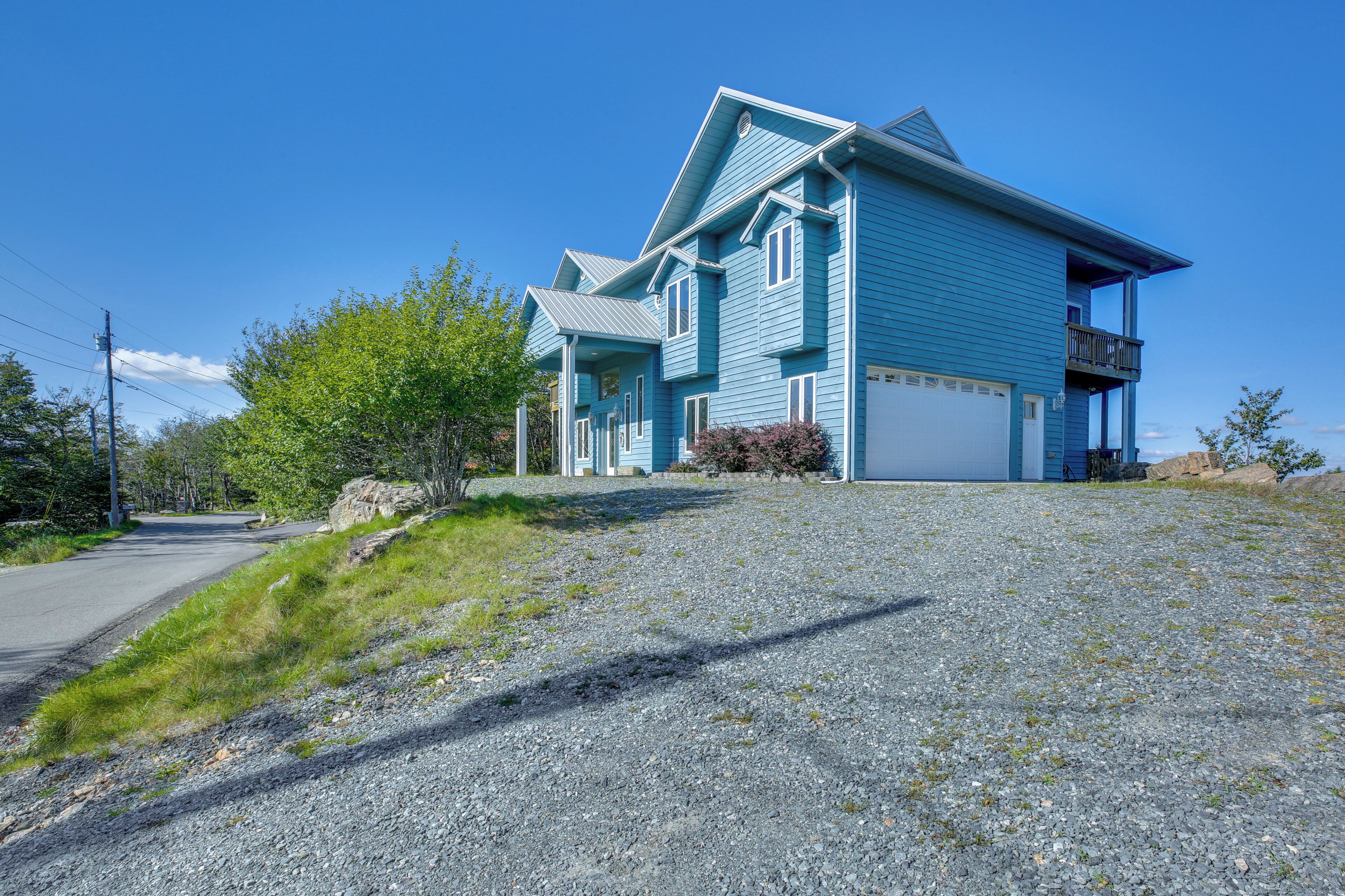 A two-story house with a garage, a balcony, and a gravel driveway.