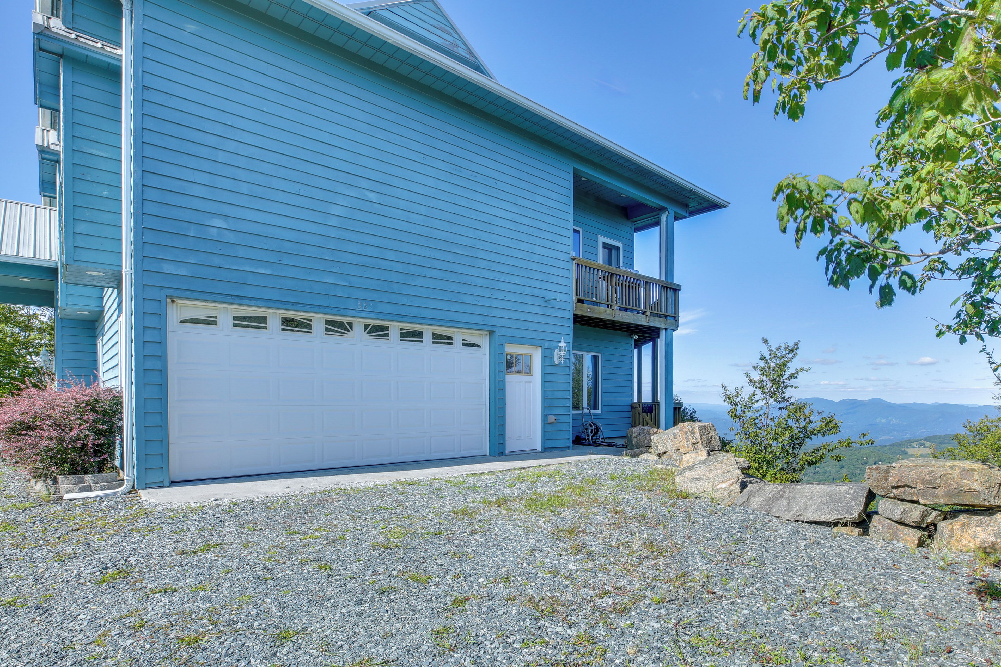 A two-story house with a white garage door, a balcony, and a view of the mountains.
