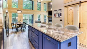 Una cocina amplia con una isla grande, armarios de madera y una zona de comedor con sillas.