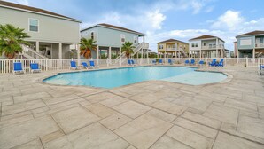 A swimming pool surrounded by a white fence, with several houses in the background. - Home w/ Pool Access in Rockport! (Rockport)