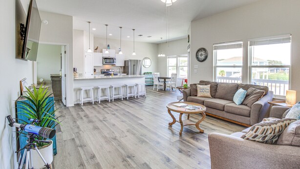 A spacious living area with a kitchen, a ceiling fan, and a large window providing natural light. - Home w/ Pool Access in Rockport! (Rockport)