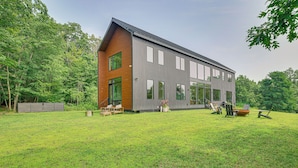 Een modern herenhuis met een ruime voortuin, houten terras en een zitgedeelte buiten.