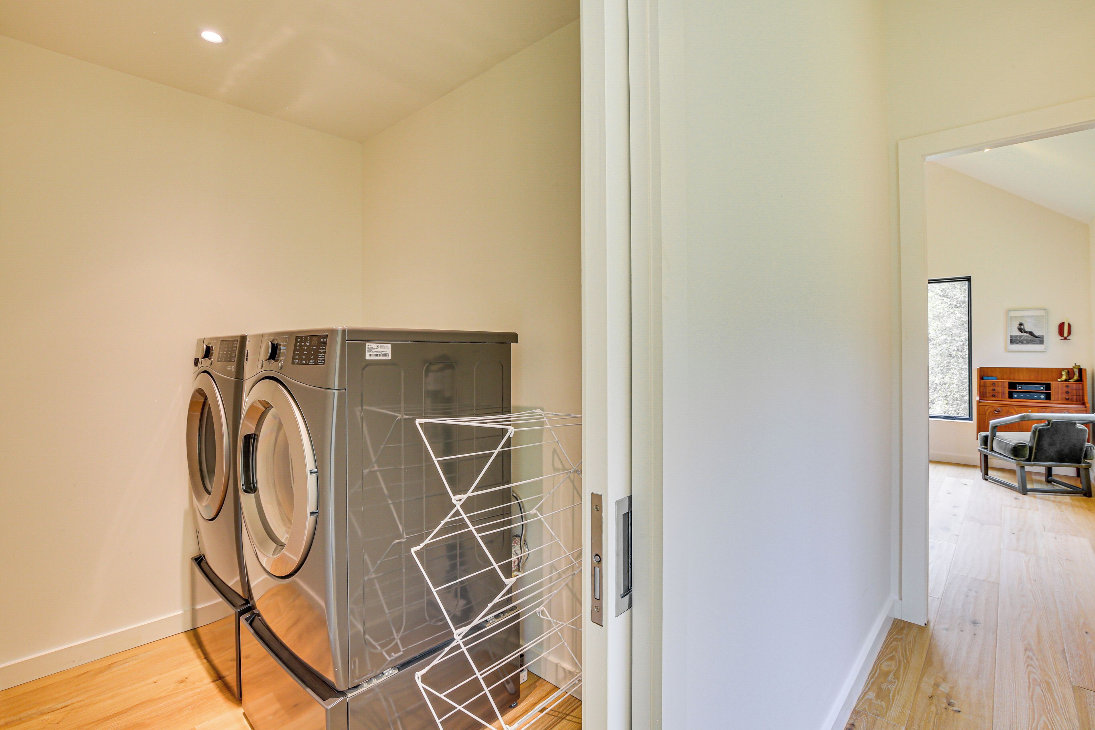 A laundry room with two front-loading washing machines and a drying rack.