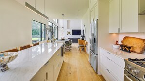 Een moderne keuken met een lange aanrecht, inbouwapparatuur en een zithoek met een bank.