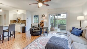 A spacious living area with a large ceiling fan, a sofa, a coffee table, and a dining area with a kitchen in the background. - Dock + Views: Scenic Group Retreat on Grand Lake! (Eucha)