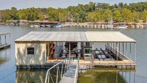 A docked boat with a covered cabin and a small dock extending into the water. - Dock + Views: Scenic Group Retreat on Grand Lake! (Eucha)