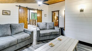 A modern living room with two grey sofas, a wooden ceiling, and a sliding barn door. - Red River Gorge Barndominium: Dog Friendly! (Beattyville)