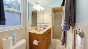 A bathroom with a sink, mirror, and shower. There are towels hanging on the wall and a toilet paper roll on the counter. - Community Perks! Mountain Home w/ Deck in Newland (Newland)