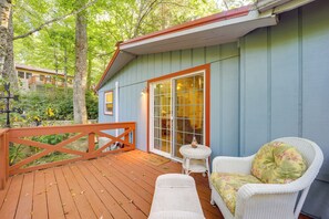 A wooden deck with wicker furniture and a glass door leading to a covered area.