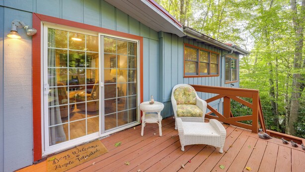 A wooden deck with a wicker chair and a small table, a glass door entrance, and a sign welcoming dogs. - Community Perks! Mountain Home w/ Deck in Newland (Newland)