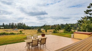 Um pátio com mobiliário externo, uma banheira de hidromassagem e vista para uma paisagem rural.