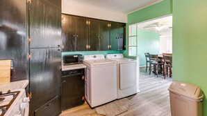 A compact kitchen with dark cabinets, a microwave, a dishwasher, and a washing machine.