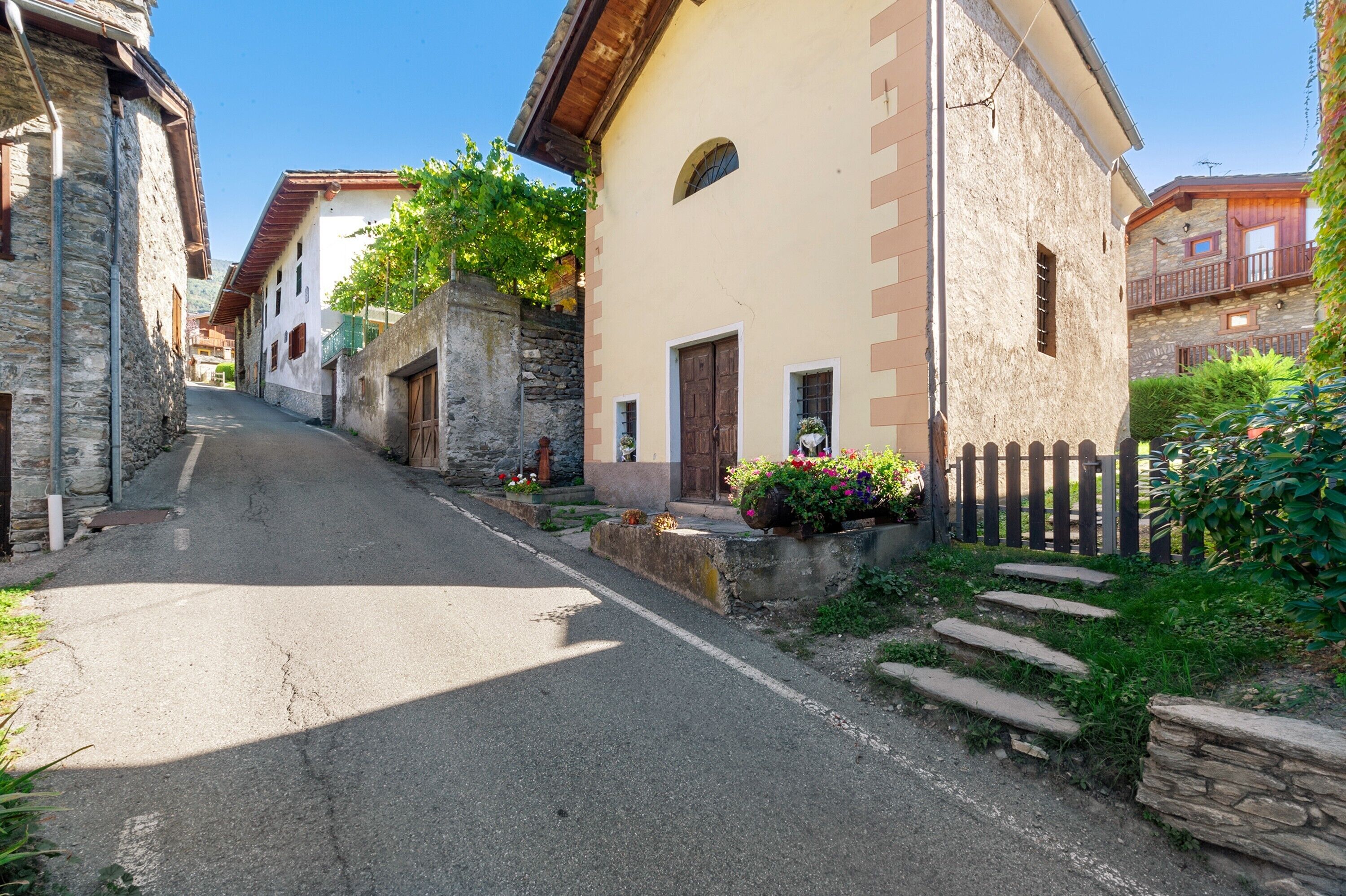 A narrow street lined with traditional stone buildings, some with balconies and flower boxes.