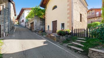 A narrow street lined with traditional stone buildings, some with balconies and flower boxes.
