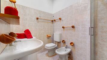 Un baño con lavamanos, inodoro, bidé y zona de ducha.