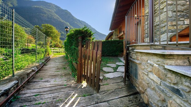 Ein Steinhaus mit einer Holterrasse und einem Metallzaun.