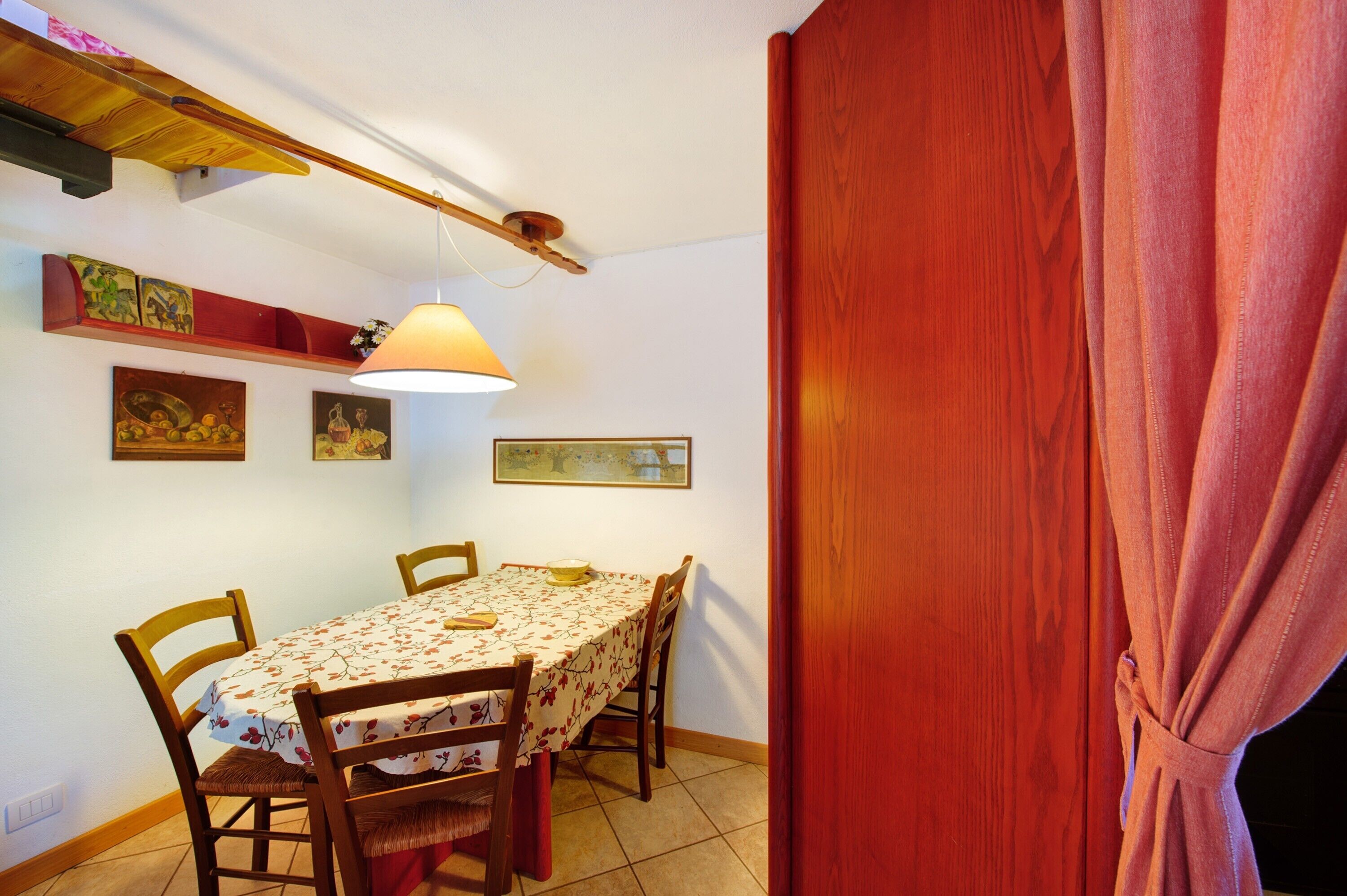 Zona de menjador amb taula, cadires, lampaderia penjant i obra d'art penjada a la paret.