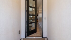 A hallway with a black-framed door leading to a room.