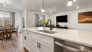 A modern kitchen with a large island, white cabinetry, and stainless steel appliances.