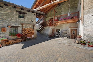 Ein Steinhaus mit einem hölzernen Balkon, einer Treppe und Außenplätzen.