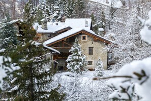 A stone building with a sloped roof surrounded by snow-covered trees.