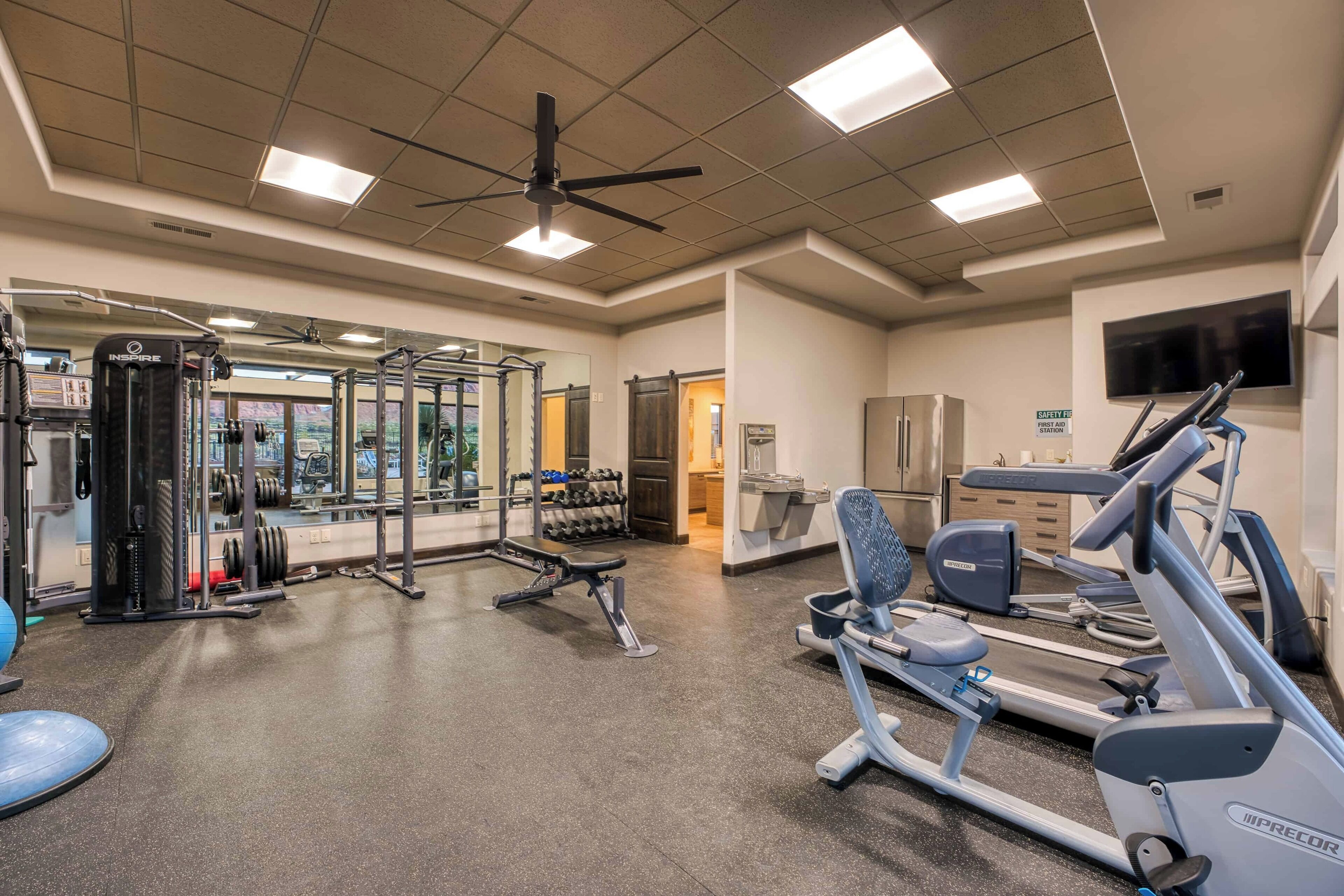 A gym with exercise equipment, a ceiling fan, and a television on the wall.