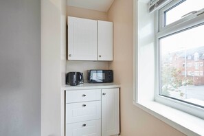 Een kitchenette met witte kastjes, een magnetron en een waterkoker.