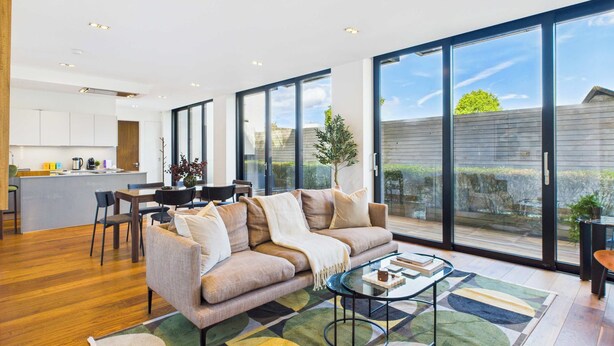 A modern living room with a sofa, coffee table, and a dining area with chairs and a table. - Stunning Camden Town Balcony Apartment (Greater London)