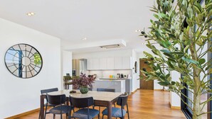 A modern dining area with a round table and chairs, a decorative vase, and a large wall clock. - Stunning Camden Town Balcony Apartment (Greater London)