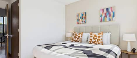 A modern bedroom with a large bed, two side tables, and abstract wall art.