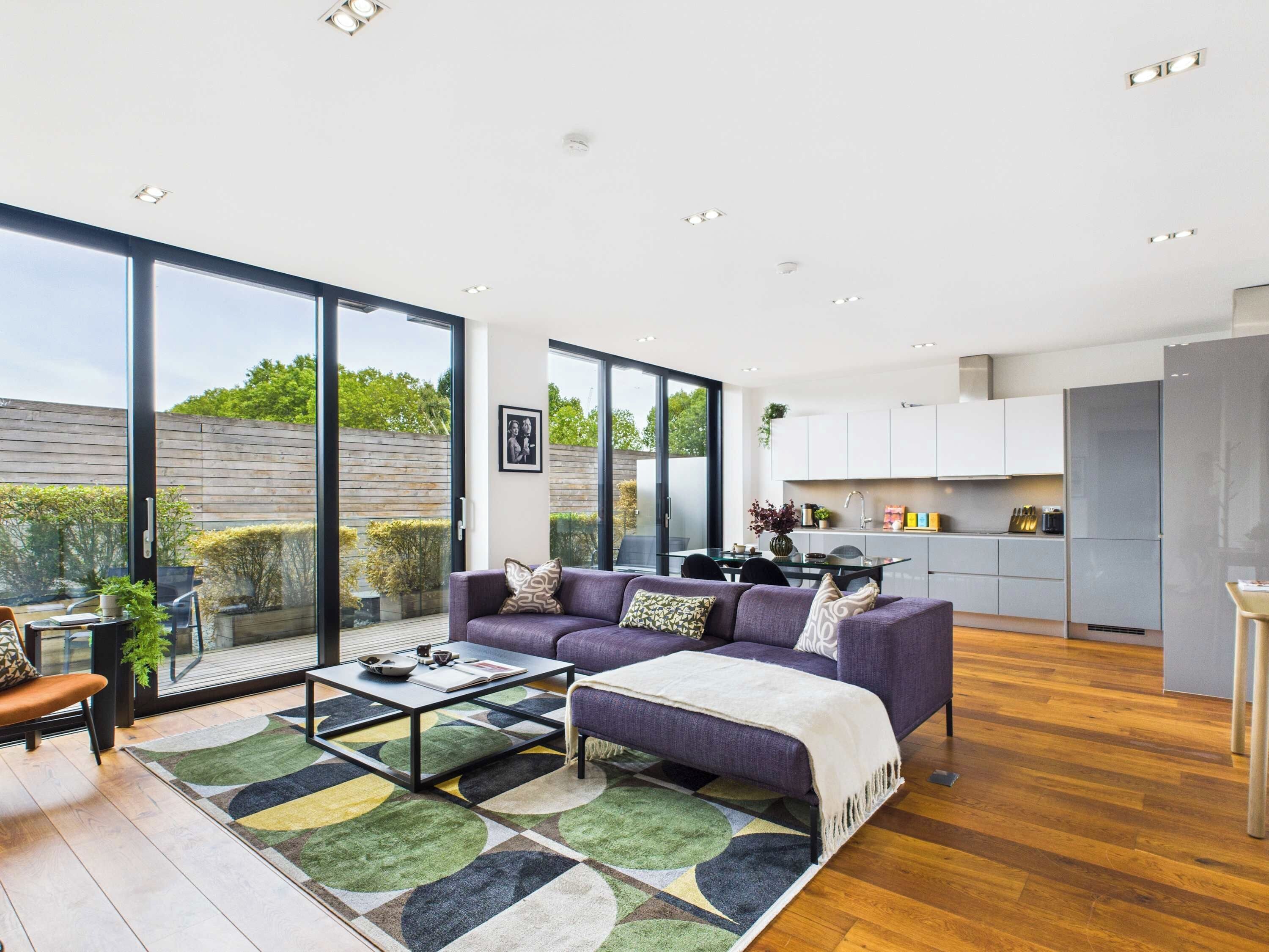 A modern living room with a sofa set, a coffee table, and a view of the garden through large sliding doors.