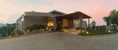 A modern building with a covered entrance, paved driveway, and outdoor seating area.